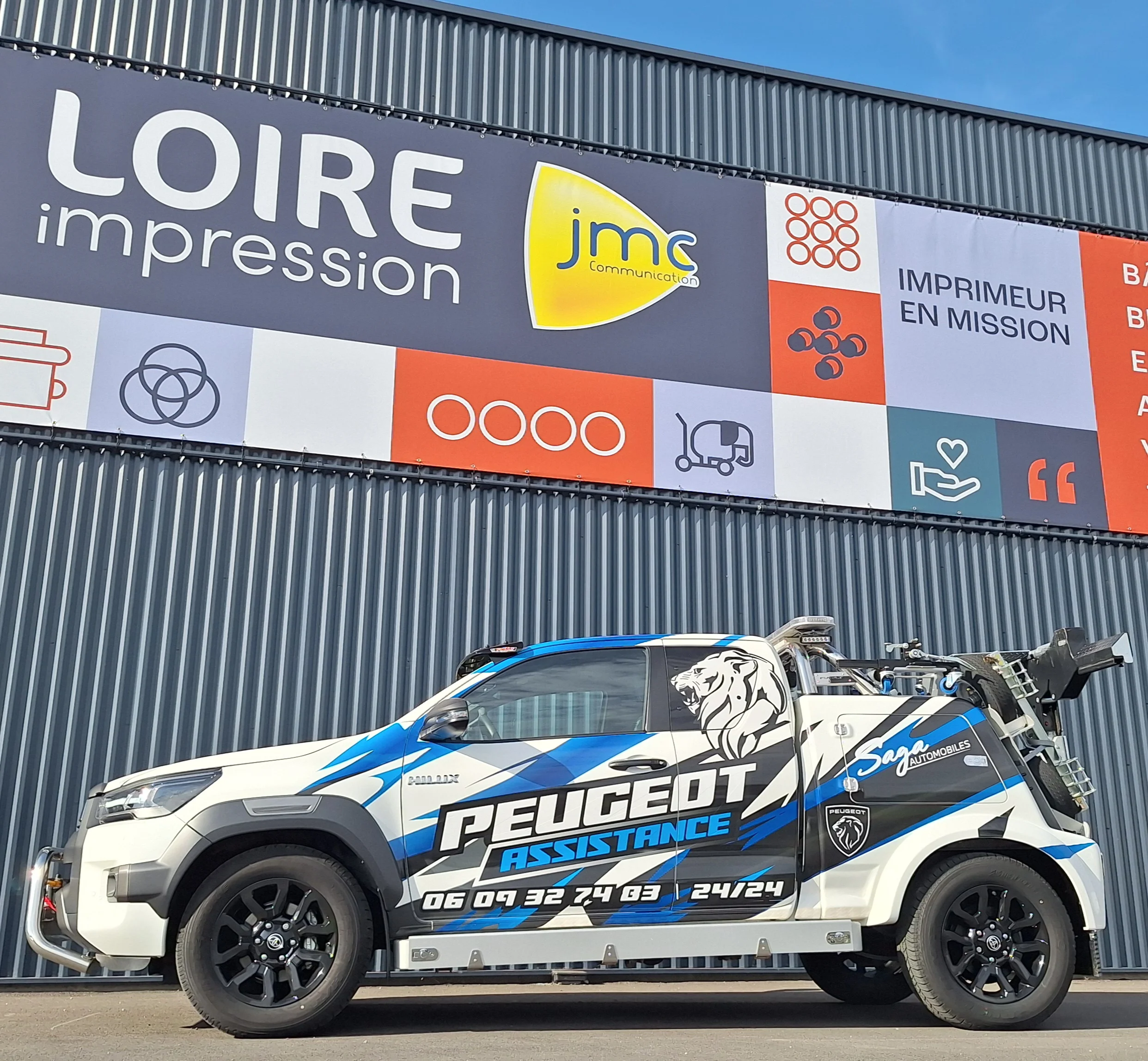 Covering publicitaire d’une dépanneuse Peugeot Assistance pour Saga Automobiles, avec marquage adhésif bleu, noir et blanc.